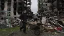 Seorang pemuda mendorong gerobak di depan gedung apartemen yang hancur di kota Borodyanka, Ukraina, pada Minggu, 10 April 2022. Invasi Rusia ke Ukraina hingga saat ini telah berlangsung selama 46 hari. (AP Photo/Petros Giannacouris)