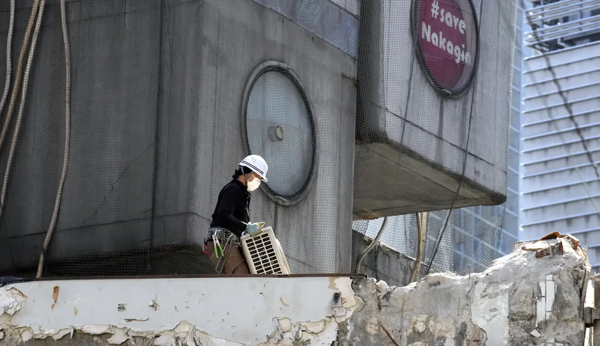 Pekerja membawa AC di lokasi pembongkaran Menara Kapsul Nakagin, bangunan ikonik yang dirancang arsitek Jepang Kisho Kurokawa pada tahun 1972, di distrik Ginza Tokyo, Selasa (12/4/2022). Pekerjaan pembongkaran menara 140 unit kapsul tersebut dimulai Selasa. (AP Photo/Eugene Hoshiko)