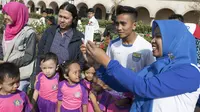Pemain Persib, Muhammad Taufiq melakukan selfie bersama anak-anak SD usai latihan di Alun-alun Kota Bandung, Jawa Barat, Kamis (10/9/2015). (Bola.com/Vitalis Yogi Trisna)