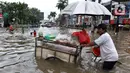 Pedagang sayur melintasi banjir yang merendam kawasan Green Garden, Jakarta Barat, Selasa (25/2/2020). Hujan yang mengguyur kawasan Jakarta membuat kawasan tersebut tergenang banjir setinggi 60-80 cm. (Liputan6.com/Johan Tallo)