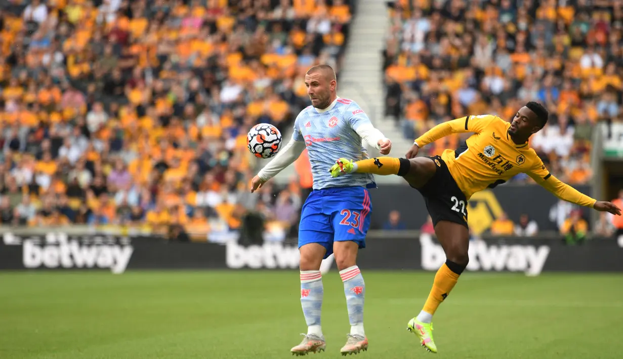 Bek Manchester United (MU) Luke Shaw (kiri) bersaing dengan bek Wolverhampton Wanderers Nelson Semedo pada match day ketiga Liga Inggris di Stadion Molineux, Minggu (29/8/2021). MU menang tipis 1-0 lewat gol Mason Greenwood. (Oli SCARFF/AFP)