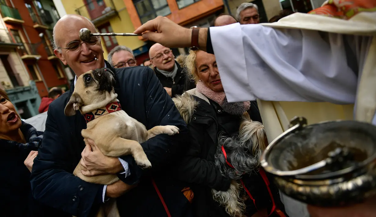 Seorang pria membawa anjingnya untuk diberkati pada peringatan Hari santo Antonius di luar gereja San Nicolas, Spanyol, Kamis (17/1). Pada perayaan tahunan itu, para pemilik membawa hewan peliharaan untuk diberkati oleh pastor. (AP/Alvaro Barrientos)