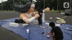 Pekerja seni menyelesaikan pembuatan patung untuk mobil hias di Silang Monas, Jakarta, Selasa (26/12/2023). (merdeka.com/Imam Buhori)