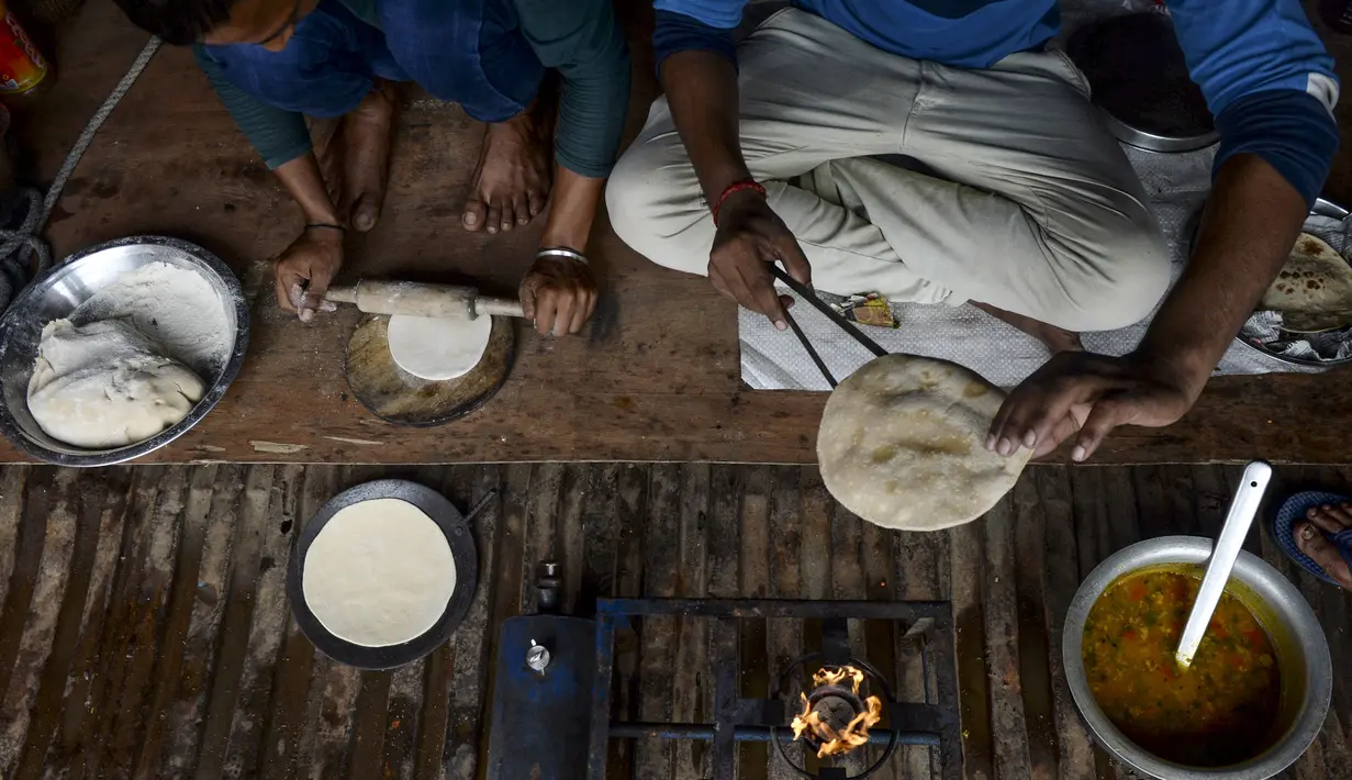 Para sopir membuat roti canai di sebuah truk yang diparkir di sebuah terminal di Chennai (19/9/2019). Semua asosiasi besar yang menjalankan truk, bus, mobil, tempo, taksi di Delhi dan Noida telah bergabung dalam protes satu hari ini. (AFP Photo/Arun Sankar)