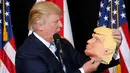 Capres dari Partai Republik Donald Trump melihat topeng wajah dirinya saat berkampanye di Sarasota, Florida, AS (7/11). Pilpres AS 2016 akan diadakan pada 8 November 2016 dan menjadi pilpres empat tahunan ke-58.  (REUTERS/Carlo Allegri) 