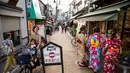 Seorang wanita mengendarai sepeda membawa anak-anaknya melihat ke arah sejumlah wanita yang mengenakan pakaian tradisional yang berbelanja di jalan Yanaka ginza di pusat Tokyo (30/9/2019). Wilayah Yanaka di ibukota Jepang dikenal sebagai salah satu yang paling kuno dan unik. (AFP Photo/Odd Andersen)