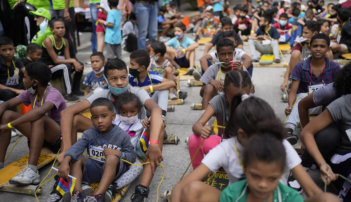 Anak-anak berpartisipasi dalam perlombaan jalanan tradisional "carruchas", sebutan untuk mobil kayu darurat di Caracas, Venezuela, Sabtu (18/12/2021). Anak laki-laki dan perempuan berusia antara 4 hingga 15 tahun berpartisipasi dalam perlombaan tersebut. (AP Photo/Ariana Cubillos)
