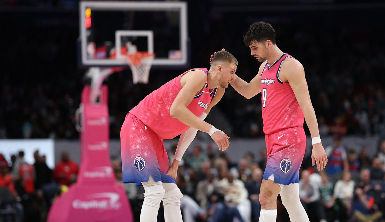 Pemain Washington Wizards, Kristaps Porzingis (kiri) berbincang dengan rekannya, Deni Avdija saat melawan Boston Celtics pada laga NBA 2023 di Capital One Arena, Washington, 28 Maret 2023. (AFP/Getty Images/Patrick Smith)