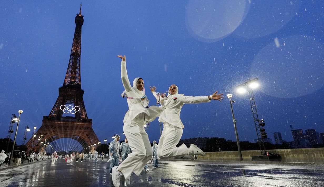 Dua orang atlet Mesir melompat di depan menara Eiffel saat acara pembukaan Olimpiade 2024 di Paris, Sabtu (27/7/2024).  (AP Photo/Andy Wong)