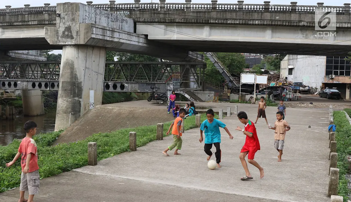 Anak-anak bermain sepak bola di jalur inspeksi Sungai Ciliwung di kawasan Rawajati, Jakarta, Rabu (23/1). Keterbatasan lahan tidak menyurutkan semangat mereka untuk bermain sepak bola meski di tempat seadanya. (Liputan6.com/Immanuel Antonius)