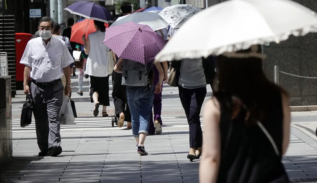 Orang-orang menggunakan payung di bawah terik matahari di Tokyo, Jepang, Selasa (10/8/2021). Menurut biro meteorologi Jepang, cuaca panas panas terus berlanjut di wilayah metropolitan saat suhu naik menjadi 38 derajat Celcius (100,4 derajat Fahrenheit). (AP Photo/Eugene Hoshiko)