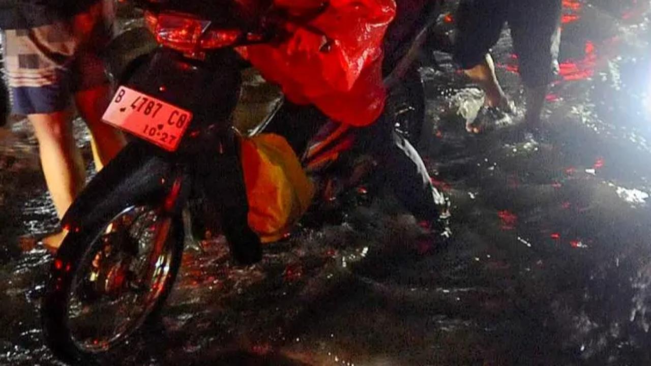 Mereka terpaksa turun untuk mendorong kendaraannya melintasi genangan banjir yang merendam jalan utama itu.