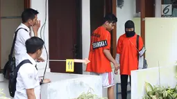Dua tersangka pembunuhan wanita yang ditemukan tewas di dalam lemari memeragakan adegan peristiwa di Tempat Kejadian Perkara di kawasan Mampang, Jakarta, Jumat (23/11). 13 adegan dilakukan tersangka dalam rekonstruksi. (Liputan6.com/Helmi Fithriansyah)