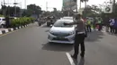 Petugas memberhentikan mobil saat penerapan ganjil genap di Jalan Raya Puncak, Gadog, Kabupaten Bogor, Jawa Barat, Jumat (3/9/2021). Pemkab Bogor menerapkan uji coba sistem ganjil genap bagi kendaraan di wilayah puncak pada tanggal 3 hingga 5 September 2021. (Liputan6.com/Herman Zakharia)