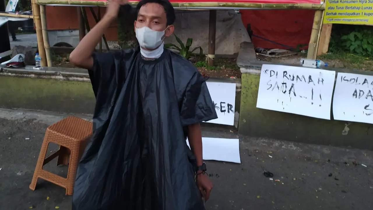 Ari Ahmad Riadi (25), salah seorang tukang cukur sekaligus seniman kota Garut, membuat pertunjukan dengan memotong rambutnya sendiri menggunakan sebuah mesin cukur, sebagai bentuk keprihatinan pemberlakuan PPKM Darurat saat ini.