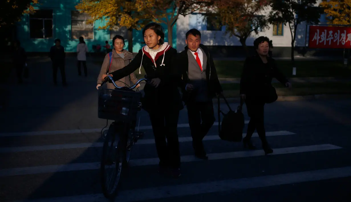 Orang-orang menyeberang jalan saat sore hari di Pyongyang, Korea Utara, (20/10). (AP Photo / Dita Alangkara)