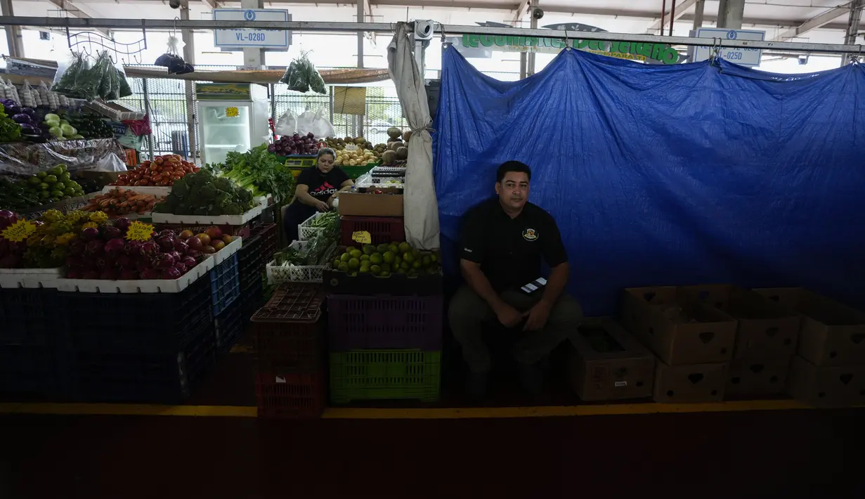 Seorang pedagang duduk di depan kiosnya yang bertirai berharap pengiriman produknya tiba di sebuah pasar di Panama City, Rabu (20/7/2022). Protes minggu ketiga dan blokade jalan raya mulai berdampak pada pasokan makanan dan barang-barang lainnya di beberapa bagian Panama. (AP Photo/Arnulfo Franco)