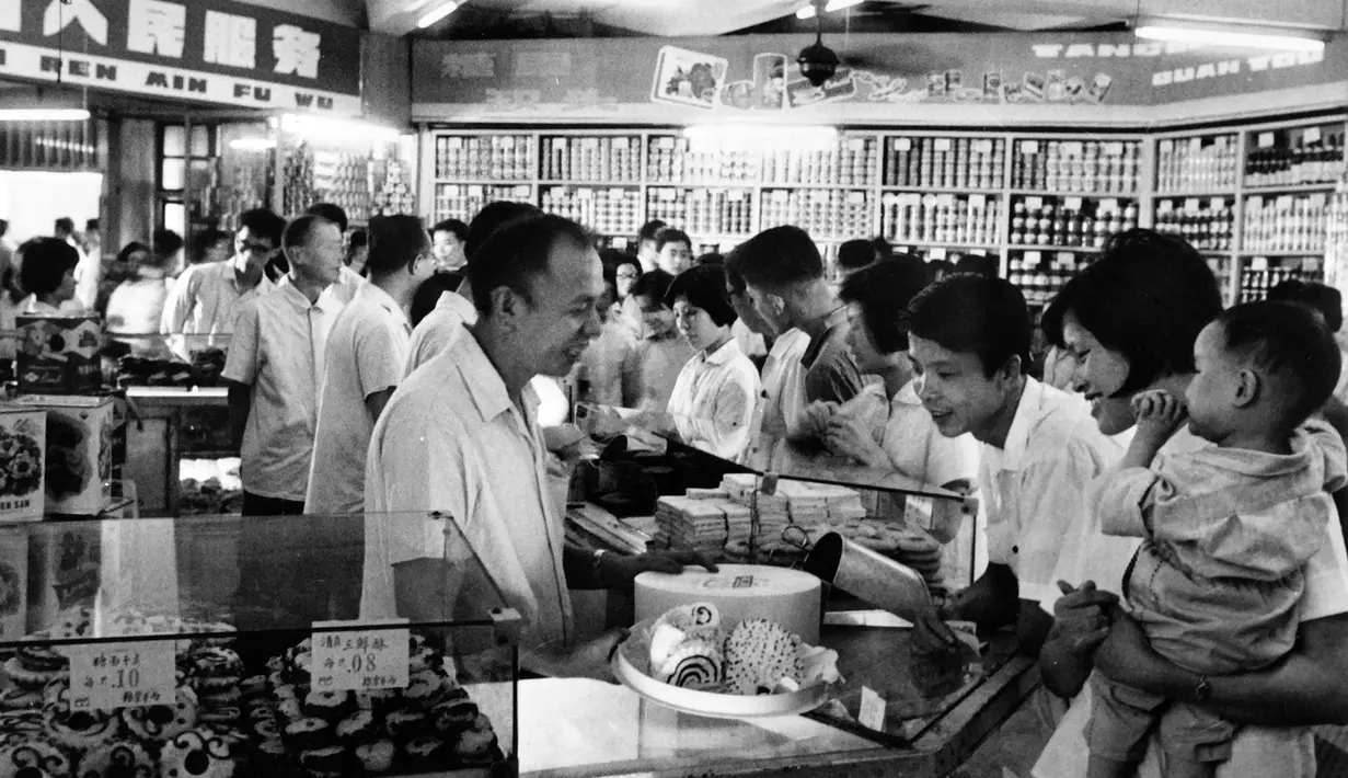 Pekerja melayani pelanggan di sebuah toko kue selama jam sibuk di Shanghai, China pada 24 September 1974. (AFP Photo)