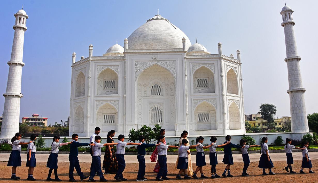 Dalam foto pada 25 November 2021 ini, anak-anak sekolah berjalan melewati replika Taj Mahal selama kunjungan mereka di Burhanpur, negara bagian Madhya Pradesh India. Pengusaha India Anand Prakash Chouksey membangun replika Taj Mahal untuk istrinya. (Uma Shankar MISHRA / AFP)