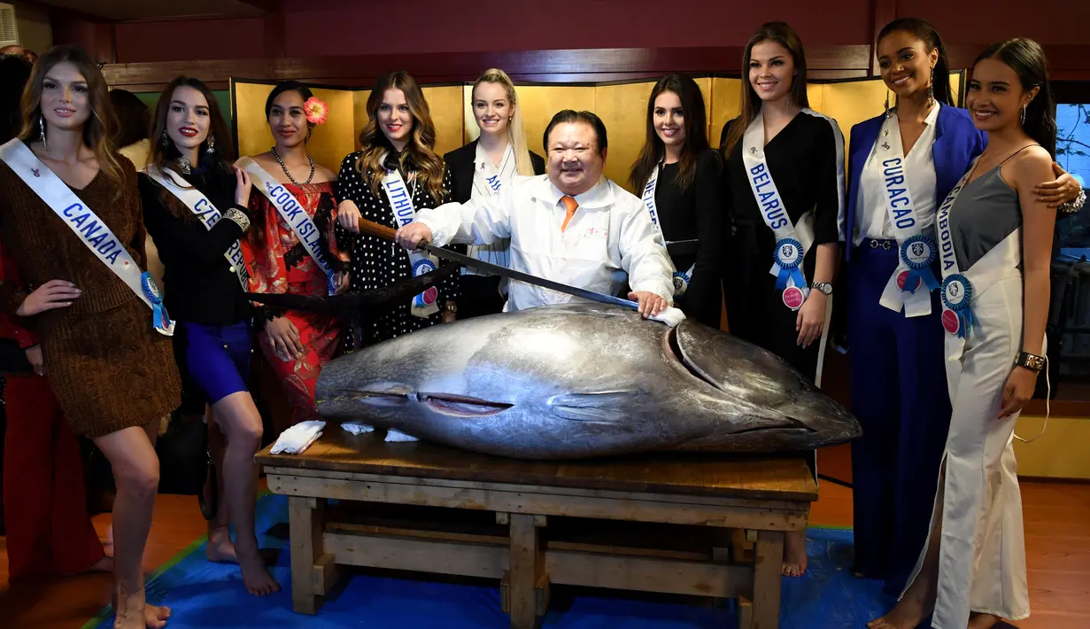 Sejumlah kontestan Miss Internasional berfoto bersama dengan Presiden Sushi-Zanmai, Kiyoshi Kimura (tengah) dan seekor tuna sirip biru seberat 250 Kg di Tokyo, Jepang (12/11). (AFP Photo/Toshifumi Kitamura)