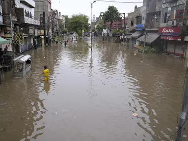 Orang-orang menyeberangi jalan yang tergenang air akibat hujan deras, di Lahore, Pakistan, Senin, 26 Juni 2023. (AP Photo/K.M. Chaudary)