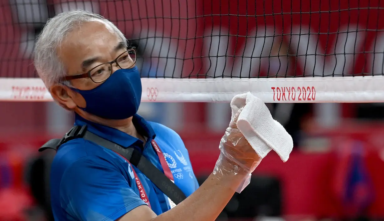 Petugas membersihkan jaring lapangan voli jelang dimulainya Olimpiade Tokyo 2020 di Ariake Arena, Tokyo, Jepang, Jumat (23/7/2021). Olimpiade Tokyo 2020 digelar dengan penerapan protokol kesehatan ketat guna mencegah penularan COVID-19. (Angela Weiss/AFP)
