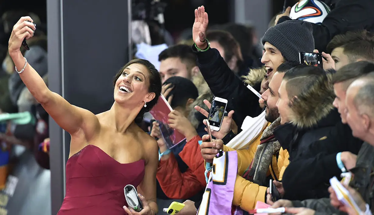 Gelandang seksi Amerika Serikat, Carli Lloyd, selfie bersama fans saat berjalan di karpet merah acara FIFA Ballon d'Or 2015 di Zurich, Swiss, Senin (11/1/2016). (AFP/Michael Bulholzer) 