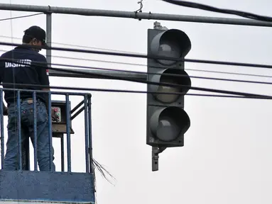 Petugas Dinas Perhubungan DKI Jakarta mengecek lampu lalu lintas di kawasan Manggarai, Jakarta, Selasa (19/7). Untuk mencegah kemacetan akibat trafic light, Dishub ganti lampu lalin yang bermasalah. (Liputan6.com/Yoppy Renato)