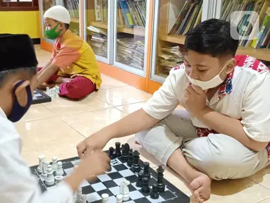 Anak-anak bermain catur di Rumah Amalia, Kota Tangerang, Selasa (23/03/2021). Selama pandemi Covid-19, rumah belajar bagi anak yatim dan dhuafa ini mengajak anak-anak bermain catur sebagai bentuk terapi agar bisa relaksasi dan mengurangi depresi selama di rumah. (Liputan6.com/Fery Pradolo)