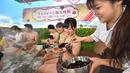 Petugas memberikan cokelat kepada pengunjung saat mandi spa cokelat di Hakone, Jepang, Senin (13/2). Mandi spa cokelat ini digelar setiap tahun bulan Februari. (AFP PHOTO / Kazuhiro Nogi)