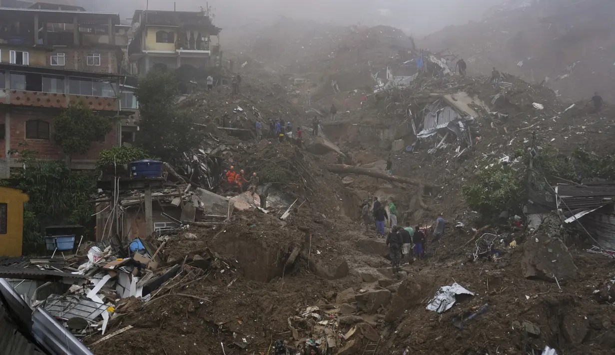 Petugas penyelamat dan penduduk mencari korban di daerah yang rusak akibat tanah longsor di Petropolis, Brasil, Rabu (16/2/2022). Hujan yang sangat deras memicu tanah longsor dan banjir di wilayah pegunungan di negara bagian Rio de Janeiro. (AP Photo/Silvia Izquierdo)