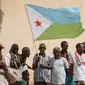Orang-orang mengibarkan bendera nasional Djibouti sambil menunggu kedatangan Presiden Djibouti Ismail Omar Guellehas sebelum upacara peluncuran proyek pembangunan rumah baru 1000 unit di Djibouti, pada 4 Juli 2018. (YASUYOSHI CHIBA / AFP)