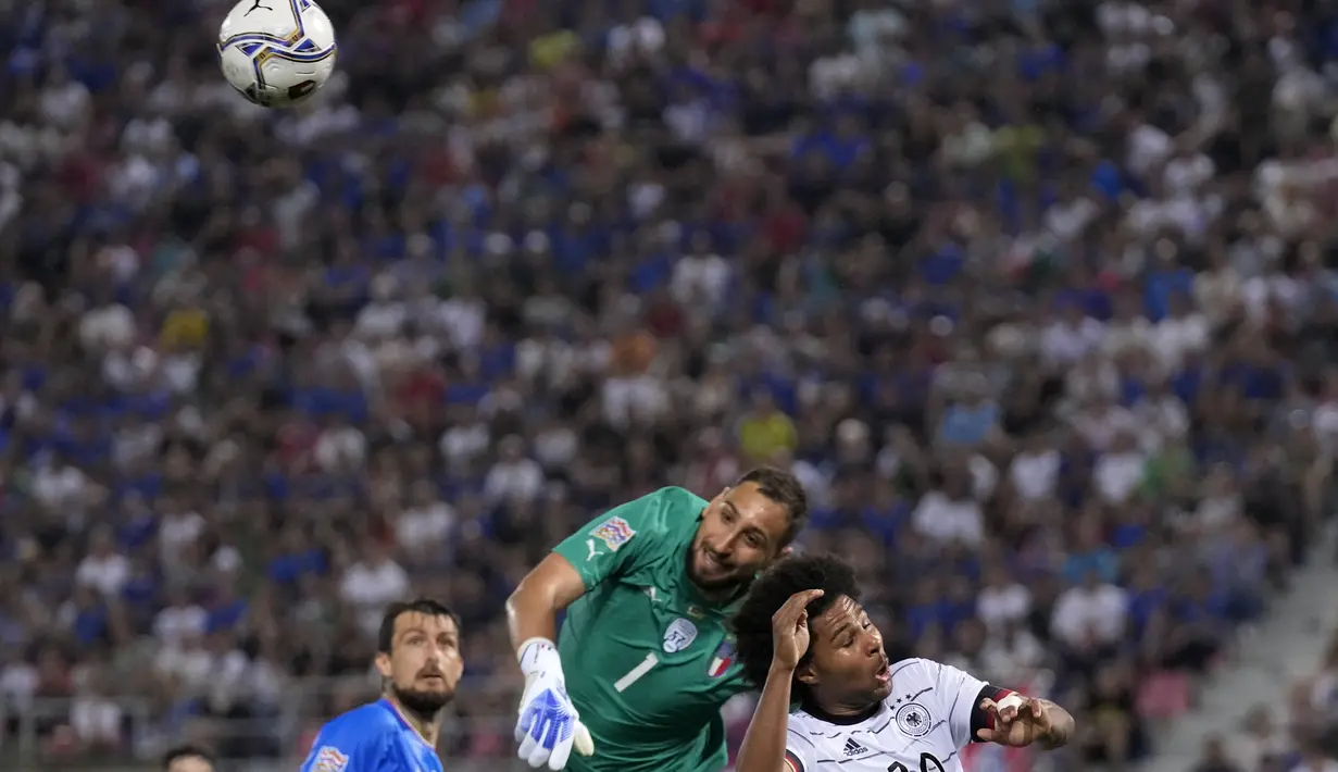 Kiper timnas Italia Gianluigi Donnarumma (tengah) melakukan penyelamatan di depan gelandang Jerman Serge Gnabry pada matchday pertama UEFA Nations League A Grup 3 di Renato Dall'Ara, Minggu (6/5/2022) dini hari WIB. Jerman bermain imbang melawan Italia dengan skor 1-1. (AP Photo/Antonio Calanni)