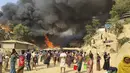 Pengungsi Rohingya menyaksikan asap membubung menyusul kebakaran di kamp pengungsi Rohingya di Balukhali, Bangladesh selatan (22/3/2021). Sejumlah orang meninggal dan 20 ribu orang mengungsi akibat kebakaran hebat di kamp pengungsi. (AP Photo/Shafiqur Rahman)