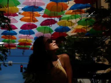 Julia Pena (19) dari Miami menikmati instalasi seni yang bernama Umbrella Sky di Coral Gables, Florida, 16 Juli 2018. Coral Gables merupakan kota ketiga di AS yang menjadi tuan rumah bagi instalasi seni yang berlangsung hingga Agustus. (AP/Brynn Anderson)