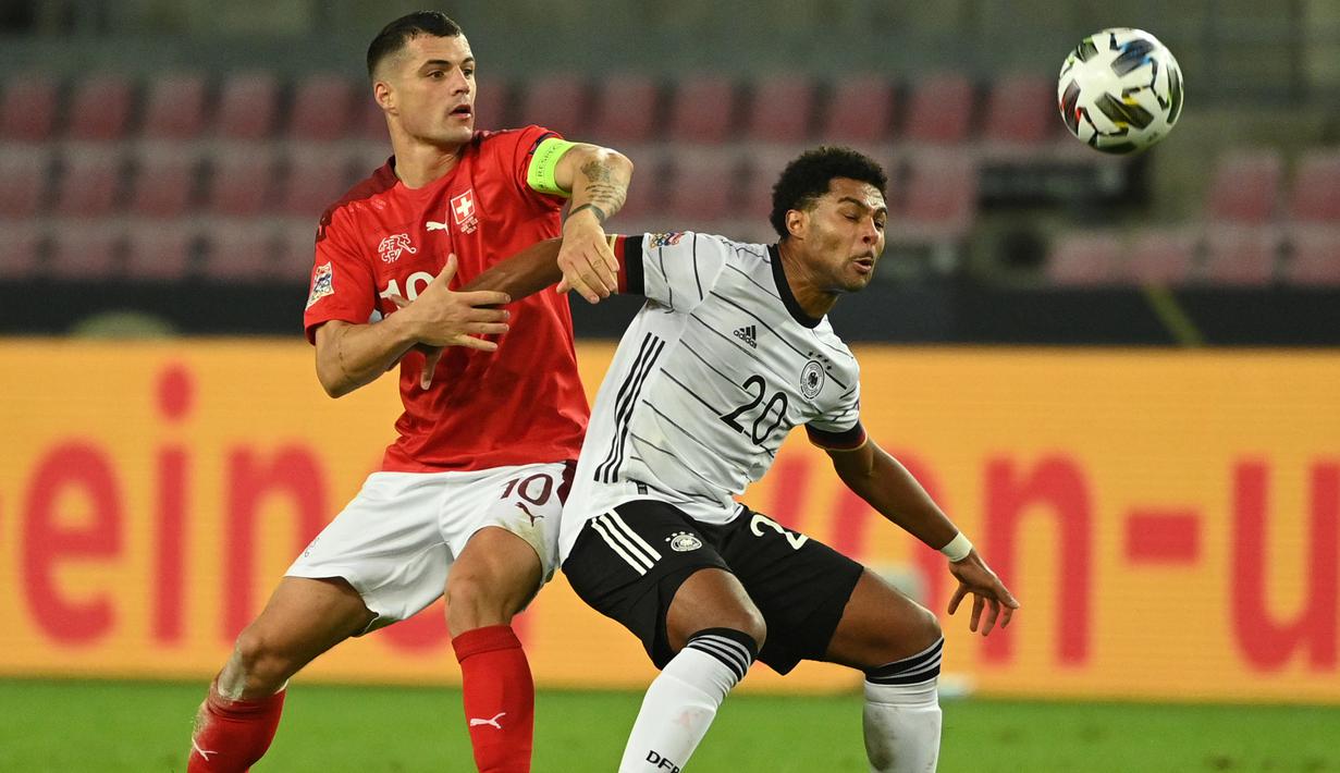 Gelandang Jerman, Serge Gnabry, berebut bola dengan gelandang Swiss, Granit Xhaka, pada laga lanjutan UEFA Nations League 2020/2021 di RheinEnergie Stadion, Rabu (14/10/2020). Jerman bermain imbang 3-3 atas Swiss. (AFP/Ina Fassbender)