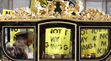 Raja Inggris Charles III dan Ratu Inggris Camilla melakukan perjalanan dengan Diamond Jubilee State Coach melewati para pengunjuk rasa yang memegang plakat "Not My King" dari kelompok anti-monarki Republik saat mereka berdemonstrasi menjelang Pembukaan Parlemen, di seberang Gedung Parlemen di London pada 7 November 2023. (HENRY NICHOLLS/AFP)