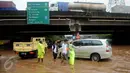 Petugas polisi mengatur lalu lintas di tengah banjir yang melanda Jalan Raya Kalimalang, Caman, Bekasi, Senin (20/2). Banyak kendaraan yang mogok karena nekat menorobos banjir dengan ketinggian sekitar 80 cm. (Liputan6.com/Gempur M Surya)