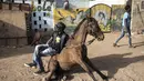 Faso Alli (kiri) berpose dengan salah satu kudanya di Ouagadougou (1/2/2022). Bagi banyak orang, budaya kuda Burkinabe memainkan peran penting dalam kehidupan mereka, mulai dari memelihara kuda untuk balap atau berpakaian, atau hingga pacuan kuda hari Minggu. acara di trek lokal. (AFP/John Wessels)