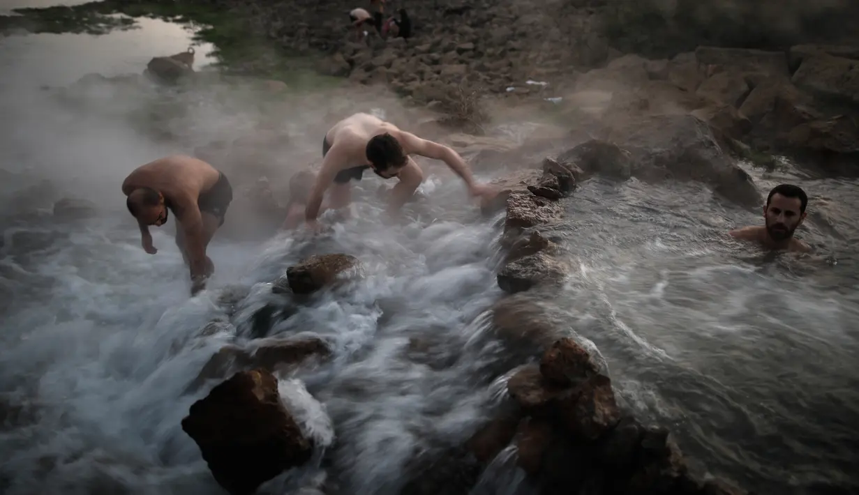 Wisatawan berenang di kolam air panas di utara Dataran Tinggi Golan yang diduduki Israel, 4 November 2017. Air mengalir dari aliran pipa pengeboran di Lembah Hula yang merupakan upaya mengurangi kekeringan di kawasan pertanian. (ENAHEM KAHANA/AFP)