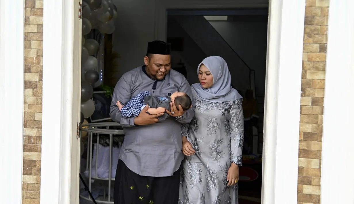 Sepasang suami istri menggendong bayi mereka yang baru lahir saat prosesi aqiqah di Banda Aceh, Aceh, 4 November 2021. Aqiqah adalah tradisi menyambut bayi yang baru lahir dalam agama Islam. (CHAIDEER MAHYUDDIN/AFP)
