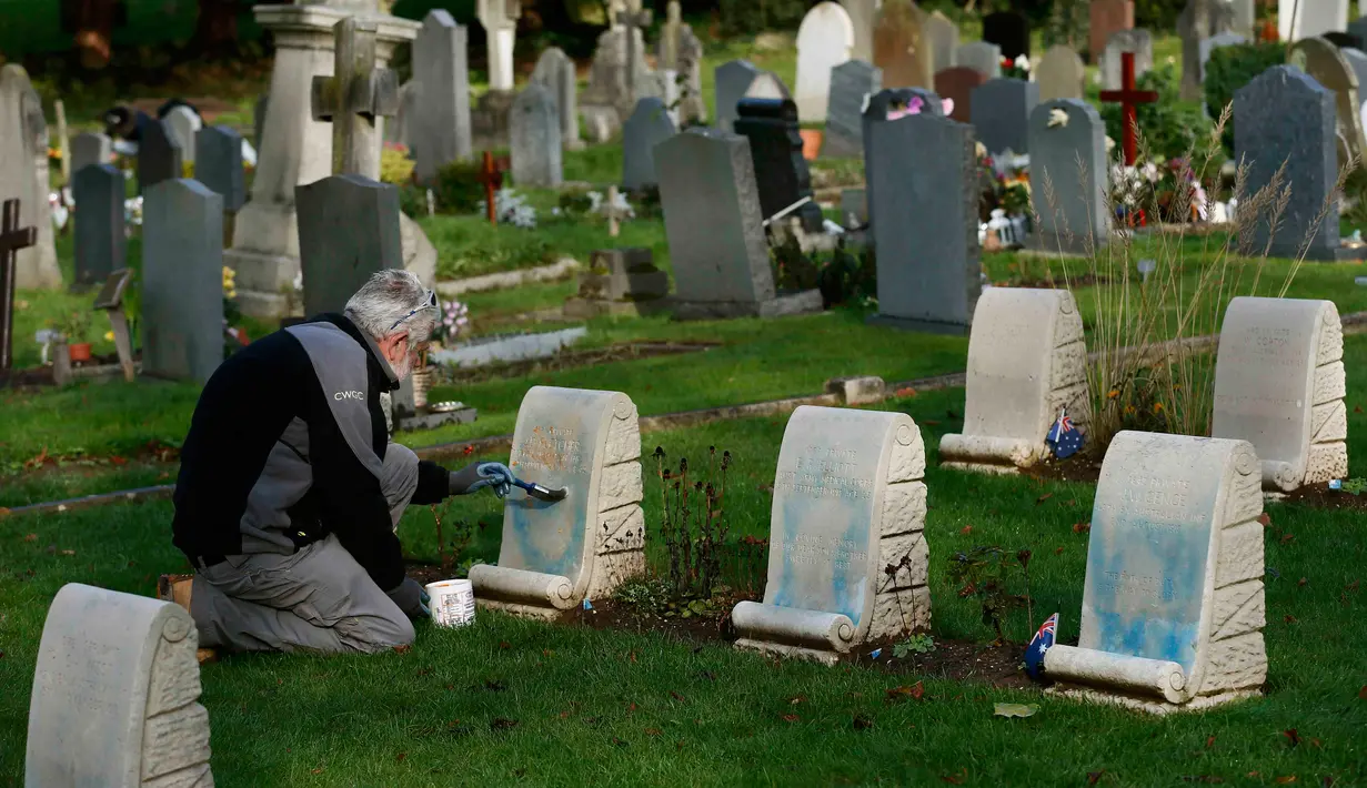 Petugas membersihkan batu nisan kuburan Harefield di Hillingdon, Inggris, Rabu (23/11). Kuburan prajurit Australia & New Zealand yang tewas pada Perang Dunia I dicoret dengan graffiti kedua kalinya dalam 7 bulan terakhir di London (REUTERS/Stefan Wermuth)