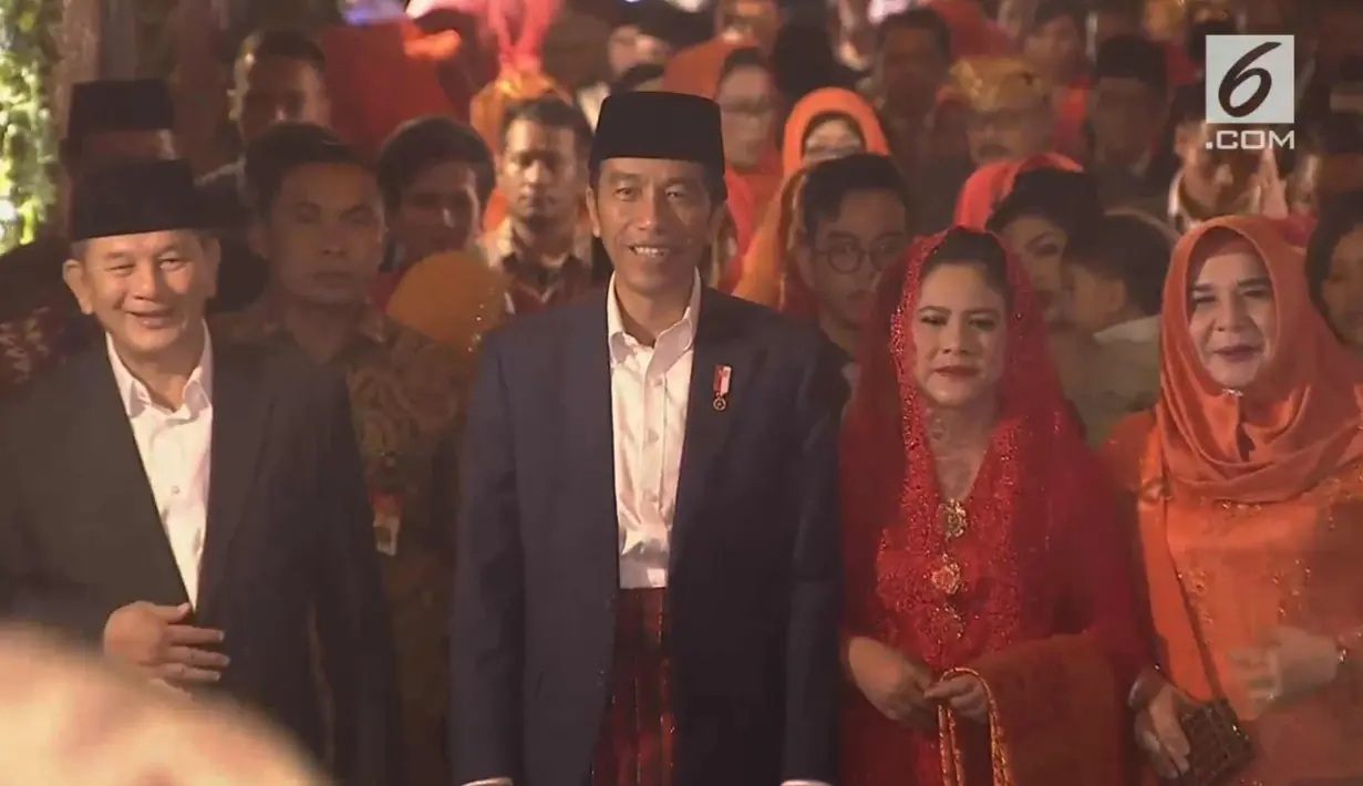 Presiden Joko Widodo dan Ibu Negara Iriana berjalan saat mengikuti prosesi penyambutan keluarga mempelai wanita secara adat di Bukit Hijau Regency Taman Setia Budi (BHR Tasbi), Medan, Sabtu (25/11). (Liputan6.com/Vidio)