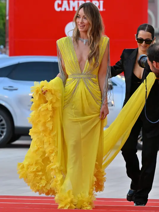 Sutradara dan aktris AS Olivia Wilde untuk pemutaran perdana film 'Don't Worry Darling' selama Venice Film Festival 2022 di Venesia, Italia, Senin (5/6/2022). Oivia Wilde mengenakan gaun kuning-hijau yang menakjubkan, dengan garis leher rendah yang hampir mencapai pusarnya, yang merupakan karya custom Gucci. (Photo by Andreas SOLARO / AFP)