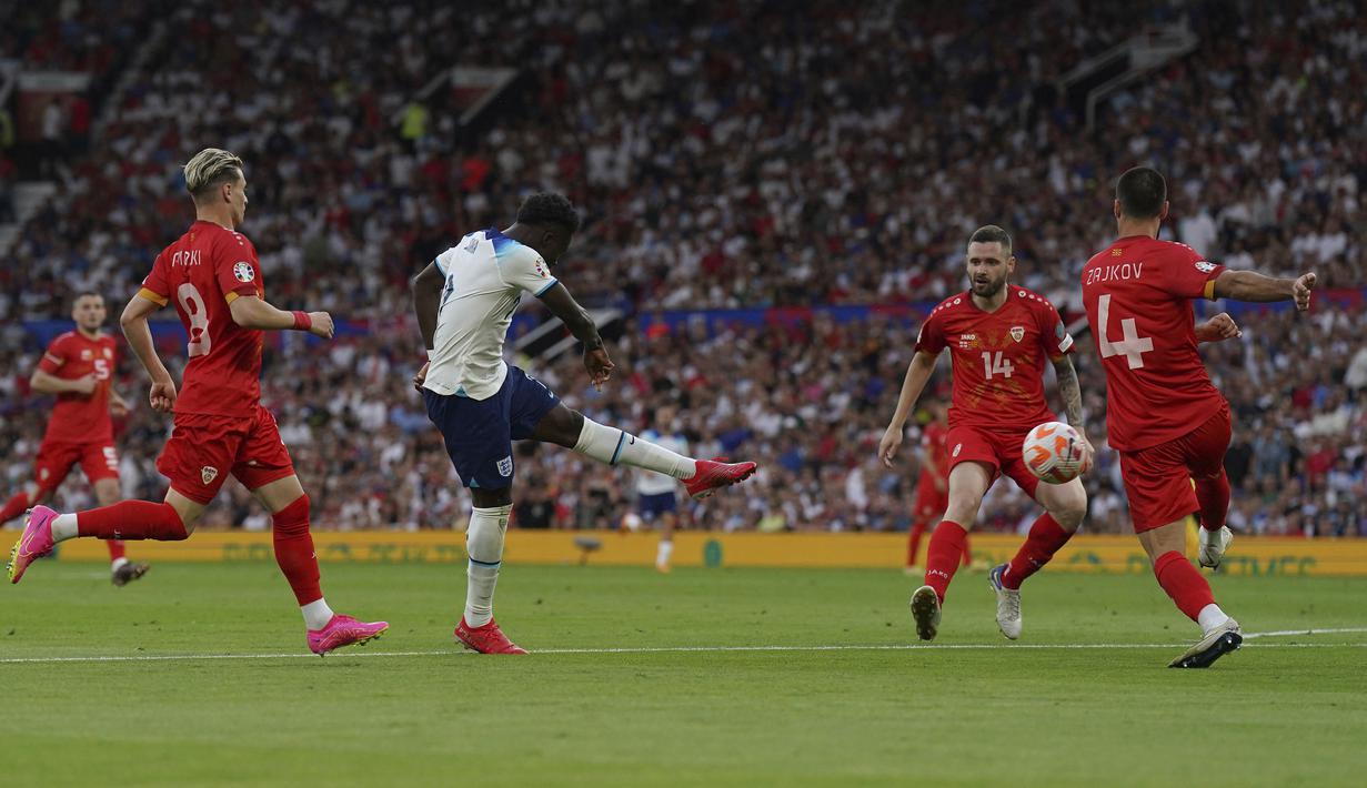Gelandang Timnas Inggris, Bukayo Saka melepaskan tendangan yang menghasilkan gol keempat Inggris ke gawang Makedonia Utara pada laga Grup C kualifikasi Euro 2024 antara Timnas Inggris menghadapi Makedonia Utara di Old Trafford, Manchester (19/6/2023). (PA via AP Photo/Tim Goode)