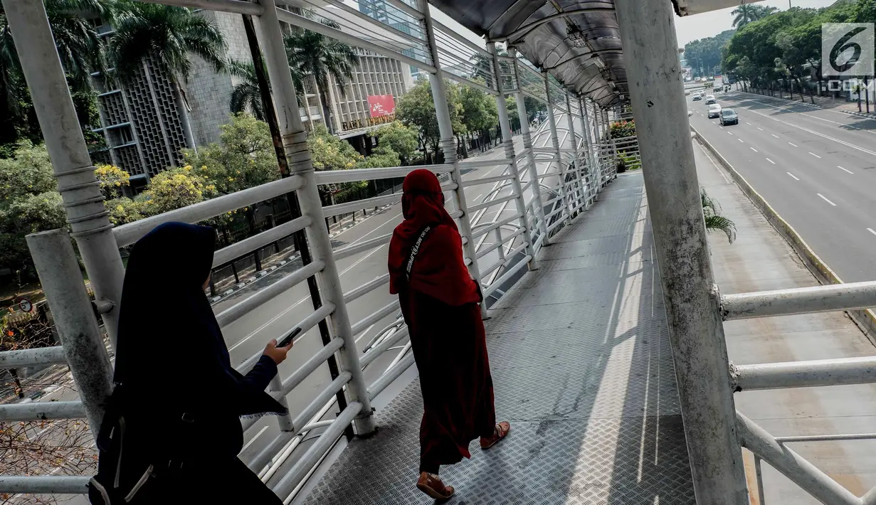 Pejalan kaki menyeberang lewat jembatan penyeberangan orang (JPO) di kawasan Jalan Thamrin, Jakarta, Sabtu (1/6/2019). Sejumlah ruas jalan rawan macet di Ibu Kota saat ini terpantau lengang dan lancar. (Liputan6.com/Faizal Fanani)
