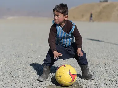 Anak laki-laki Afganistan, Murtaza Ahmadi, sedang bermain bola di Kabul, Afganistan, (1/2/2016). Lionel Messi berharap bisa bertemu dengannya setelah melihat foto Murtaza Ahmadi memakai jersey Messi dari plastik di internet. (AFP/Shah Marai)