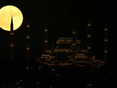 Bulan purnama terbit di belakang masjid Camlica di Istanbul, Turki, Senin (3/7/2023). Bulan purnama penuh yang dijuluki Buck Moon yang muncul pada 3 Juli menjadi supermoon pertama tahun ini. (AP Photo/Francisco Seco)