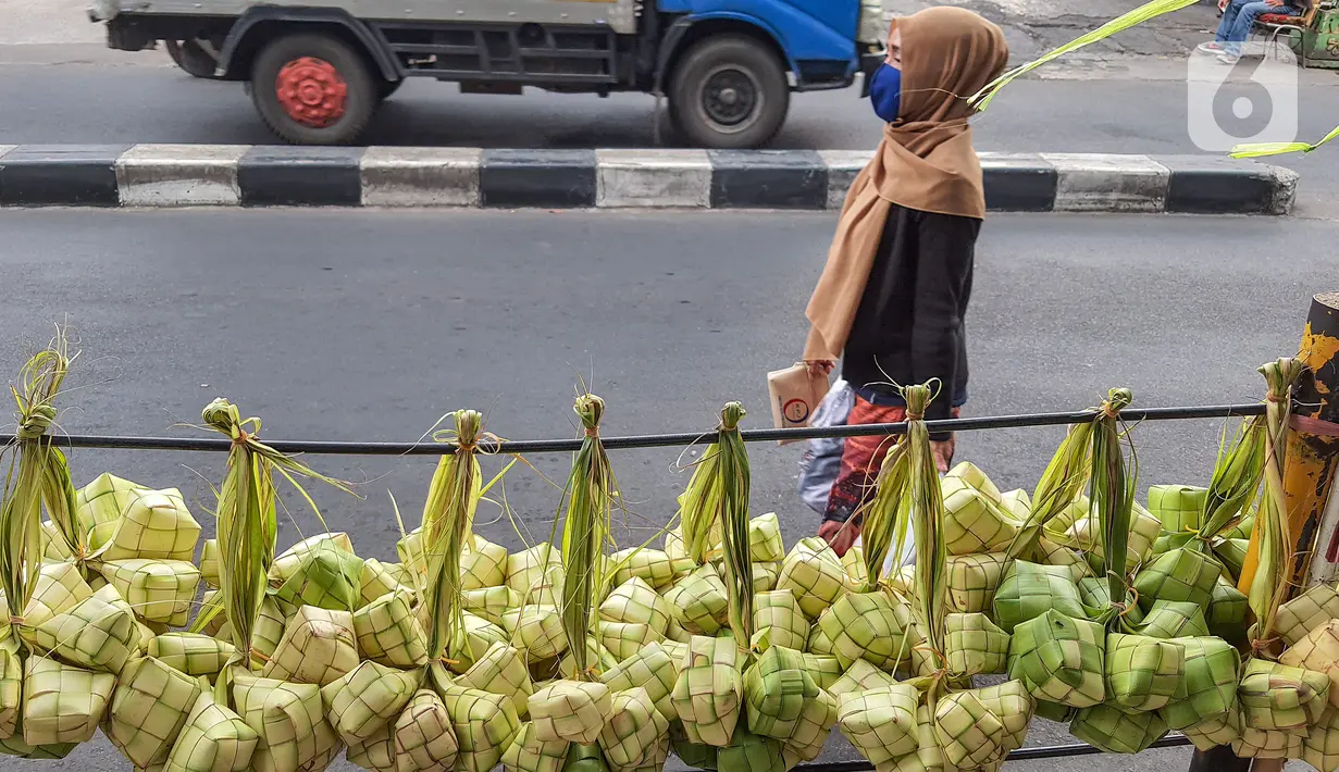 Warga melintas depan pagar yang digantung kulit ketupat dari anyaman daun kelapa muda (janur) di Pasar Pondok Labu, Jakarta Selatan, Kamis (30/7/2020). Memasuki Hari Raya Idul Adha ketupat yang merupakan hidangan khas Asia Tenggara disajikan pada saat Hari Raya. (Liputan6.com/Fery Pradolo)