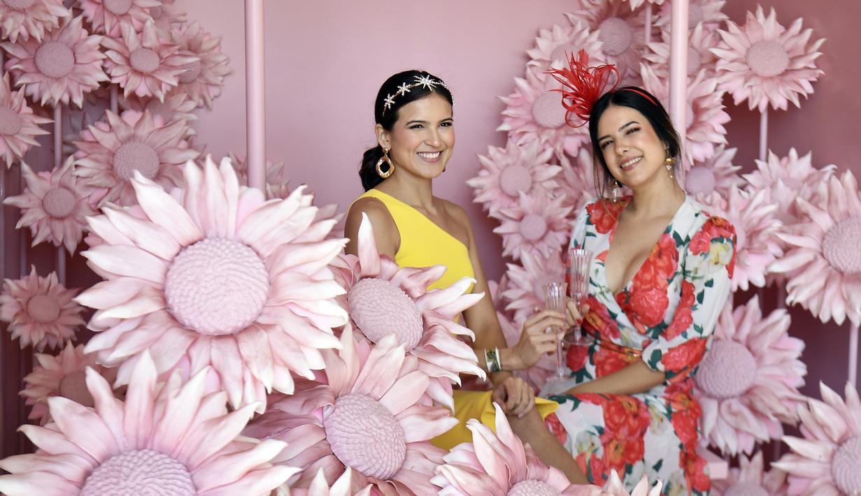 Dua wanita berpose sebelum pertandingan pacuan kuda Piala Melbourne di Melbourne (5/11/2019). Para wanita tampil cantik dan modis dengan hiasan kepala yang mereka gunakan selama menyaksikan balap kuda di Melbourne Cup.  (AFP Photo/William West)